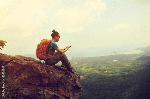 successful woman hiker reading electronic book hiking on mountain peak