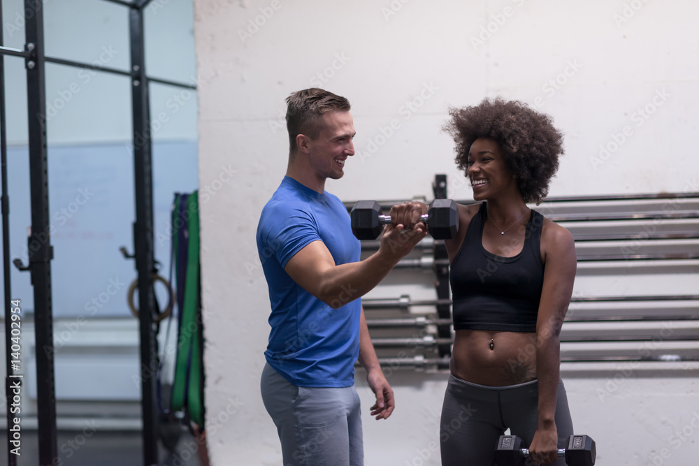 Obraz premium black woman doing bicep curls with fitness trainer