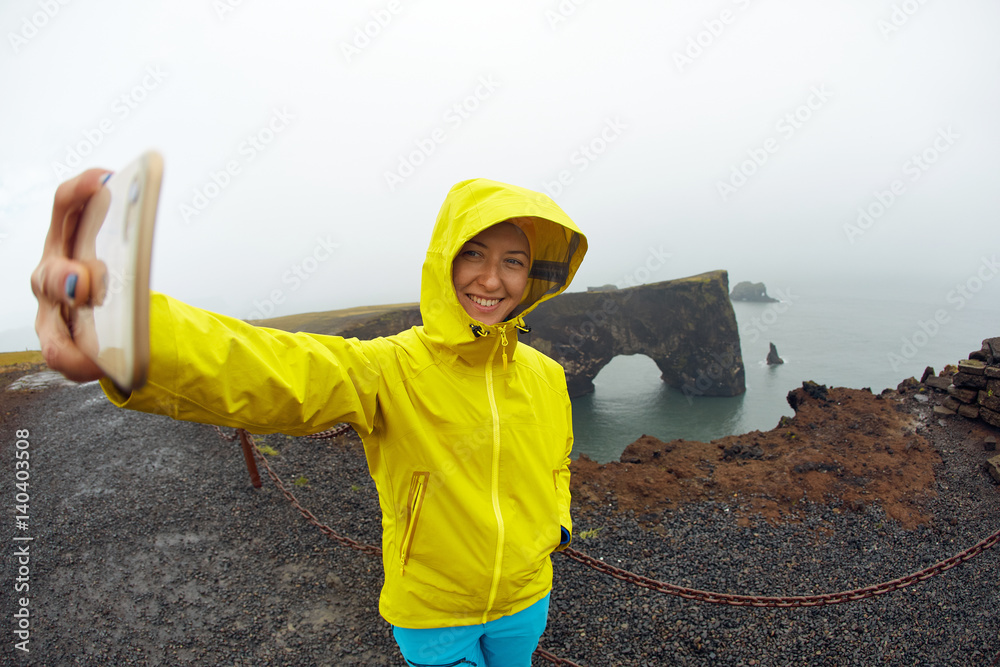 Φωτογραφία woman hiker traveler photographer taking selfie on the ocean background in rainy