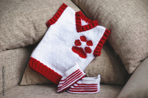 Handmade white and red knitted baby's bootees and baby vest with a dog paw embroidery