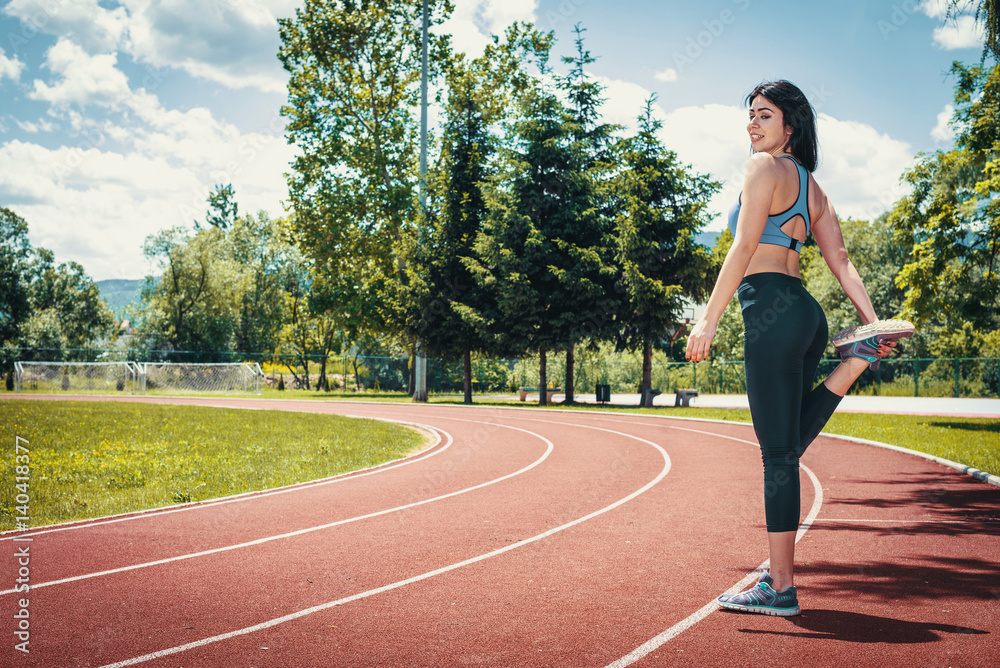 Girl doing stretching exercises on track Girl doing stretching exercises on track