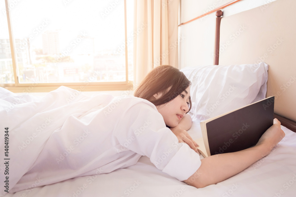 Woman reading book and drinking coffee on bed during the morning Woman reading book and drinking coffee on bed during the morning