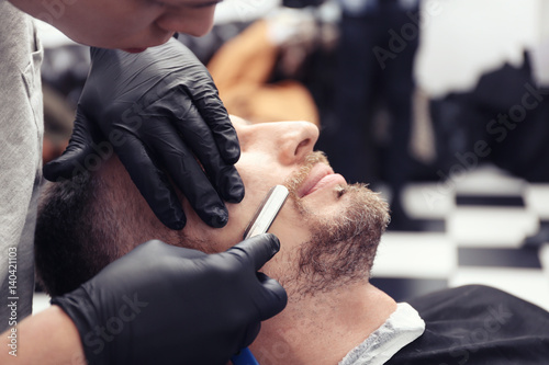 Hairdresser shaving client ...
