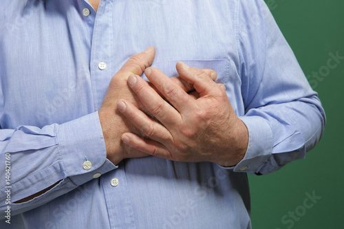 Elderly man holding hands on chest suffering from heart attack, closeup © Africa Studio