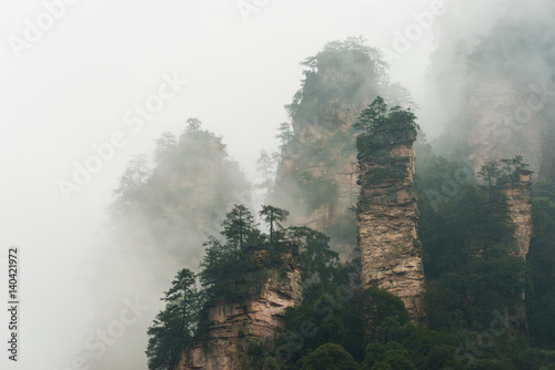 mountains are surrounded by clouds at Zhangjiajie, a national park in China known for its surreal scenery of rock formations. © superjoseph