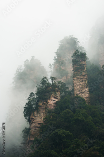 mountains are surrounded by clouds at Zhangjiajie, a national park in China known for its surreal scenery of rock formations. © superjoseph