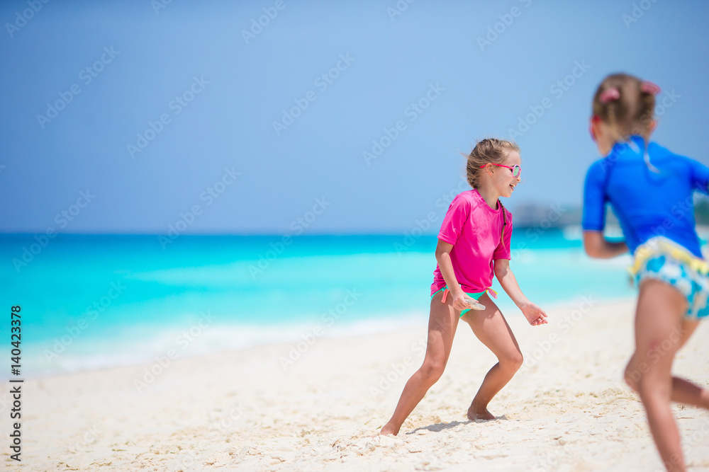 Little girls having fun at tropical beach during summer vacation playing together at shallow water