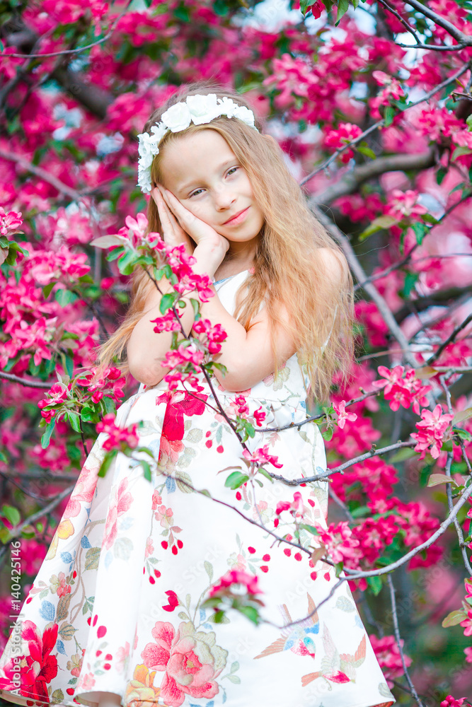 Adorable little girl in in blooming apple tree garden on spring day Adorable little girl in in blooming apple tree garden on spring day