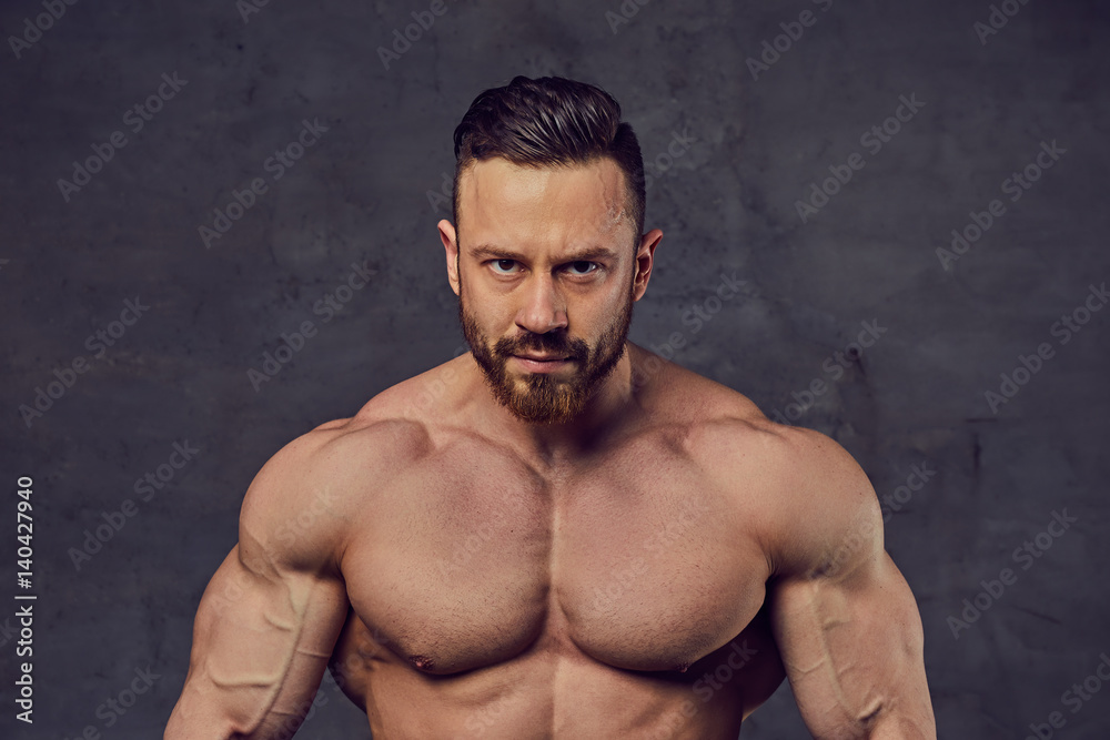 Fototapeta premium Shirtless bearded bodybuilder over grey background.