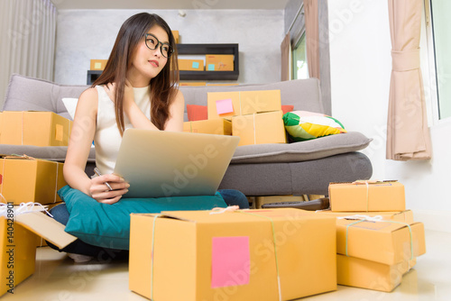 Asian beautiful girl entrepreneur relax ้her body after hard work to packing goods for send to customers and check order on her laptop