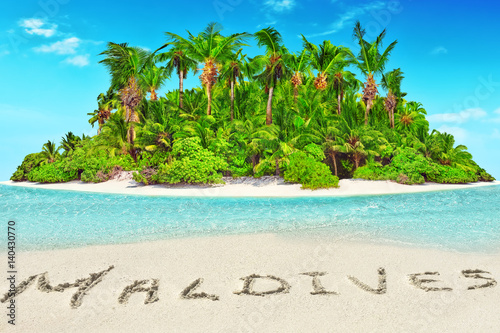 Whole tropical island within atoll in tropical Ocean and inscription "Maldives" in the sand on a tropical island,  Maldives. © BRIAN_KINNEY