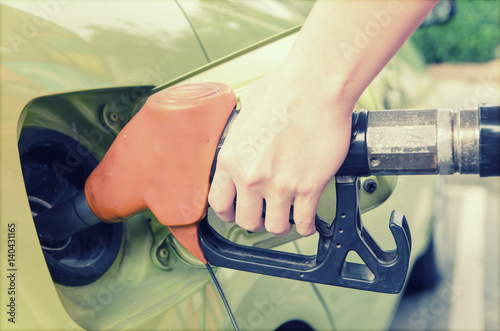 Women hold Fuel nozzle to add fuel in car at gas station