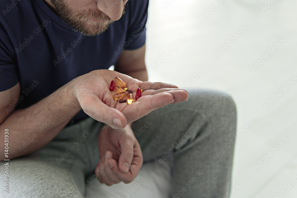 Depressed male person keeping tablets