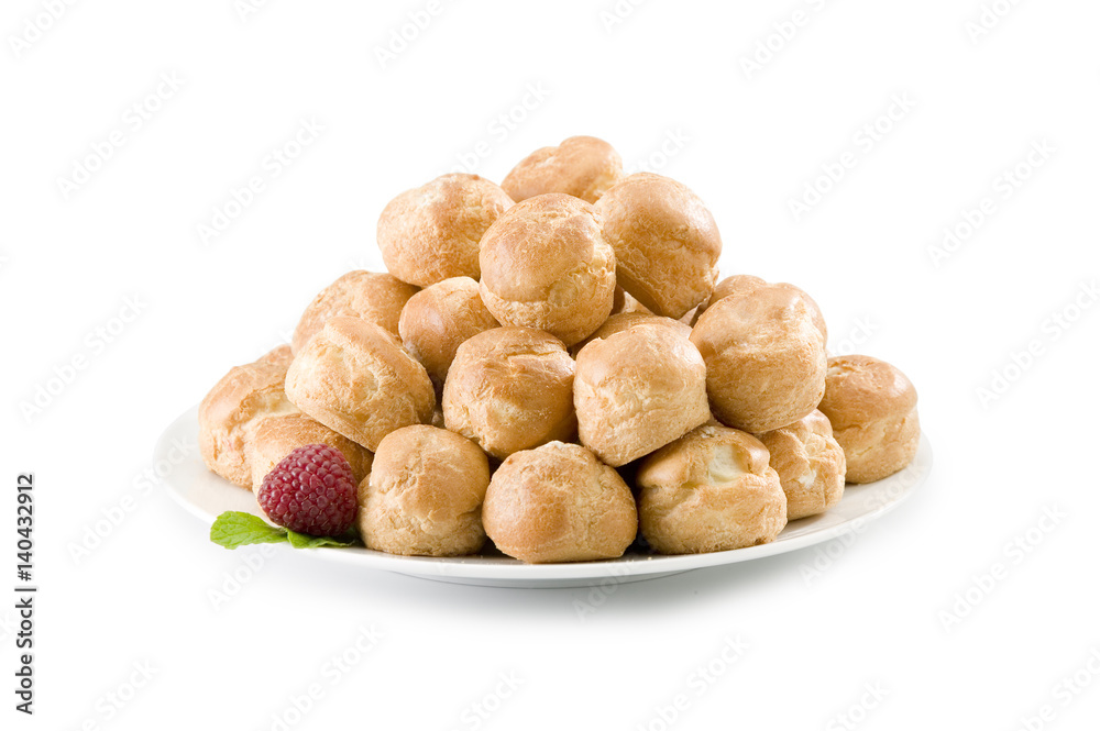 Pile of cream puffs on white plate with raspberry and mint Pile of cream puffs on white plate with raspberry and mint