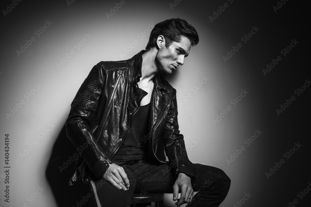 young man in leather jacket resting on a chair