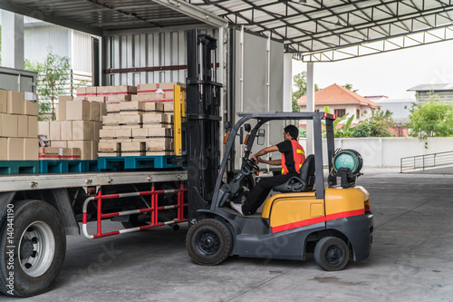 Worker loading pallet with a forklift into a truck photo