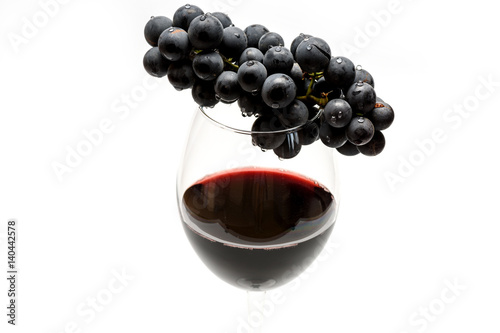Glass of red wine and grapes isolated on white background