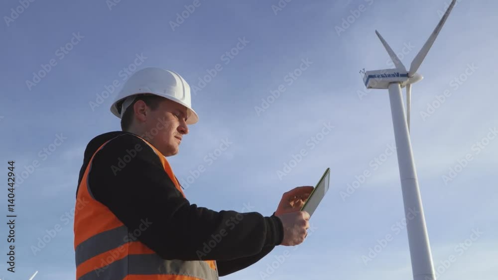 Energy Engineer of the windmill to work with the tablet at sunset. environmental Energy Engineer of the windmill to work with the tablet at sunset. environmental