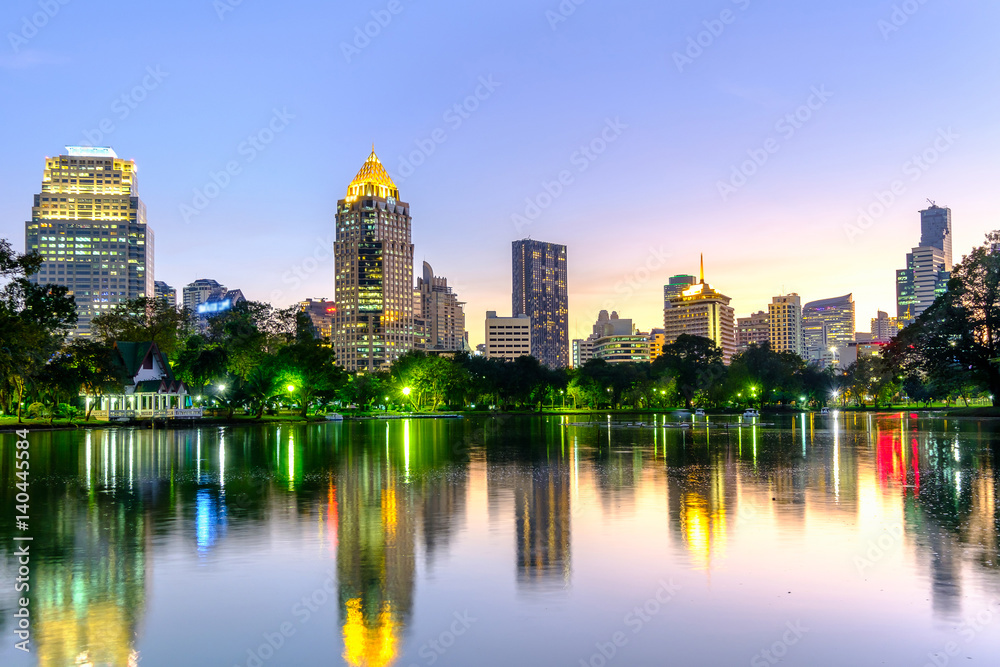 Naklejka premium Pejzaż dzielnicy biznesowej z parku w porze nocnej.