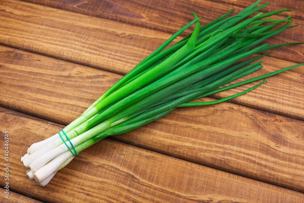 Bunch of fresh green onions laying on a wooden table. Bunch of fresh green onions laying on a wooden table.