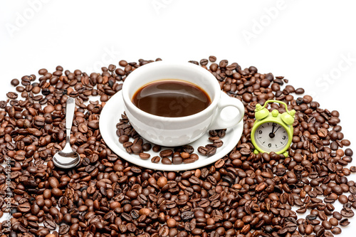 Coffee beans with cup of coffee and small alarm clock