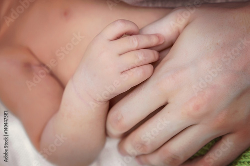A tiny hand of a newborn baby in the hand of the mother.