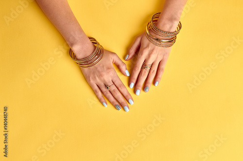 Well-groomed female hands with gold bracelets and rings.