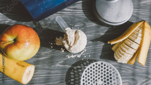 Fototapeta Naklejka Na Ścianę i Meble -  Top view of fruit and scoop of protein on a wooden background. Healthy lifestyle and sports nutrition