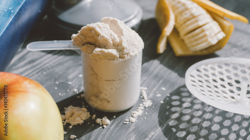 Fototapeta Naklejka Na Ścianę i Meble -  Top view of fruit and scoop of protein on a wooden background. Healthy lifestyle and sports nutrition