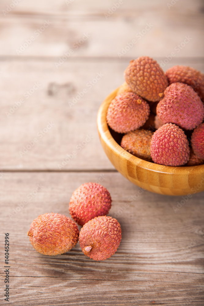 Fruits lychee in a bowl on a wooden background. Selective focus. Copy space. Fruits lychee in a bowl on a wooden background. Selective focus. Copy space.