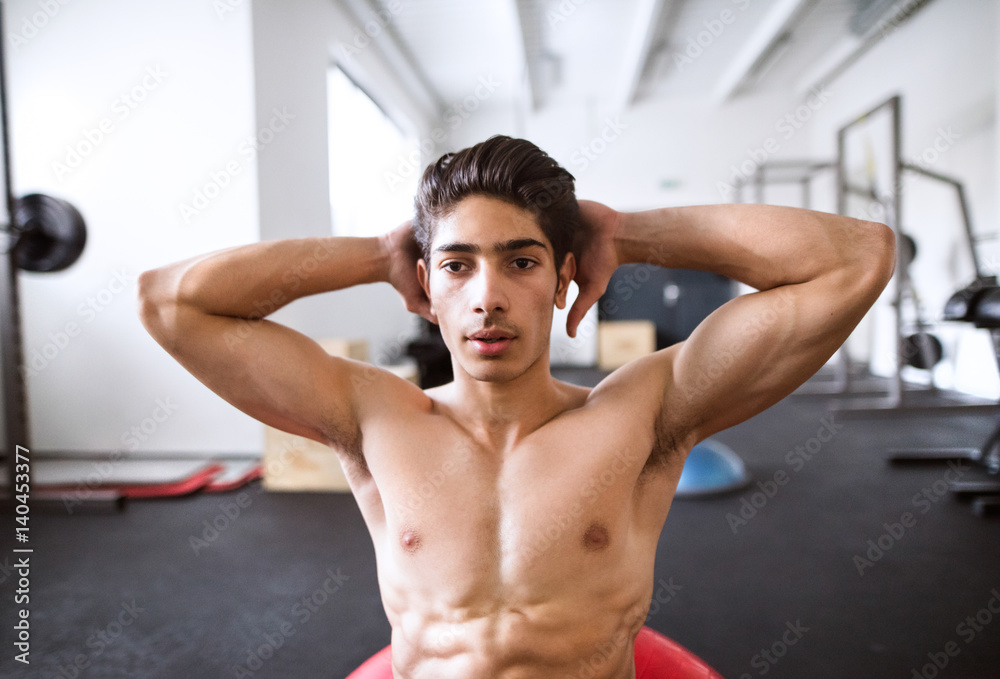Fit hispanic man in gym training, working abs, doing crunches Fit hispanic man in gym training, working abs, doing crunches