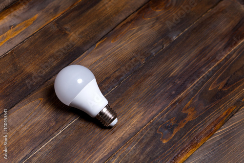 White LED light bulb on wooden background