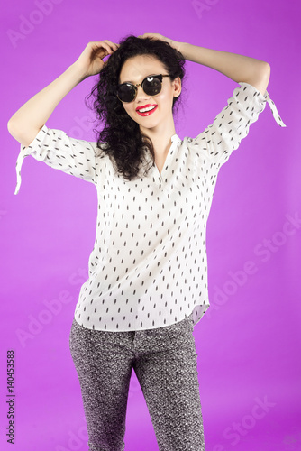 young curly brunette woman with a beautiful smile on a pink background © romanets_v