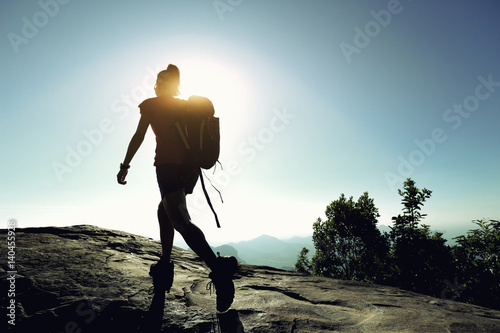 Tableau sur toile successful woman backpacker hiking on sunrise mountain top