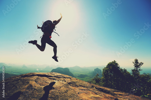 Fototapeta freedom woman backpacker jumping on sunrise mountain top