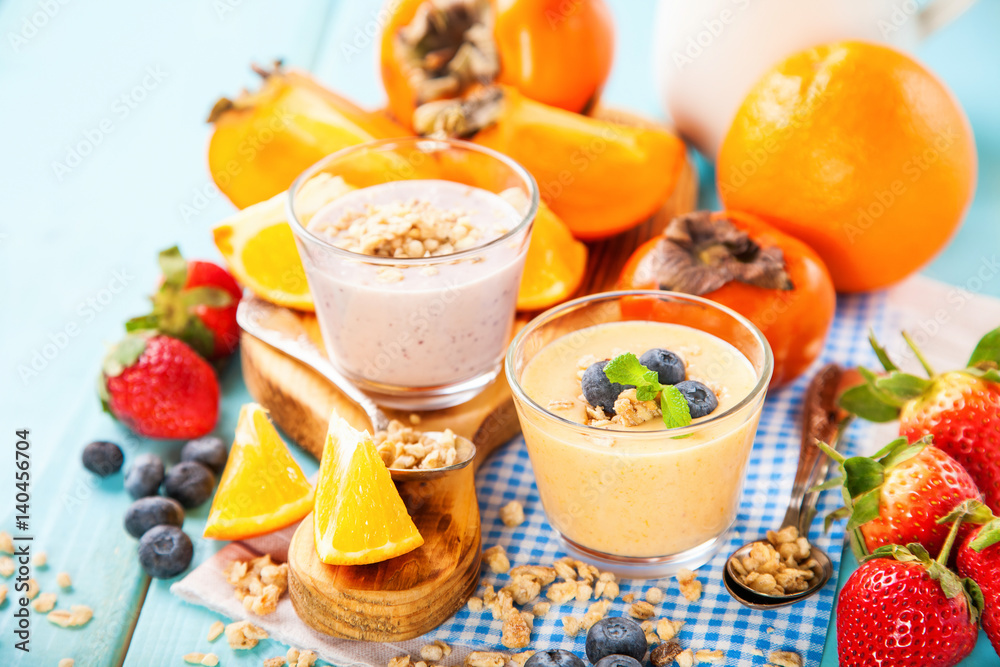 Orange persimmon blueberry smoothie with granola and fruits. Selective focus. Copy space Orange persimmon blueberry smoothie with granola and fruits. Selective focus. Copy space