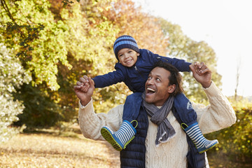 Autumn Walk With Father Carrying Son On Shoulders