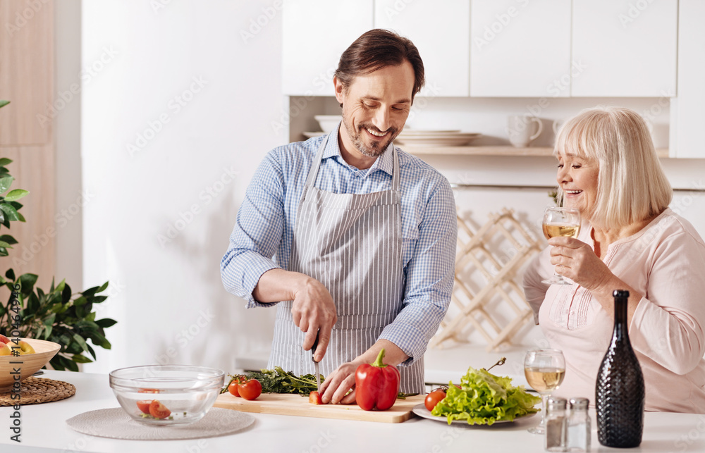 Skillful son helping aged mother in the kitchen Skillful son helping aged mother in the kitchen