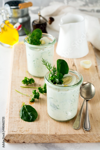 Two glasses of healthy yogurt with a variety of herbs, spinach, dill, onions, parsley and quail eggs. The concept of a healthy vegetarian breakfast. Selective focus.