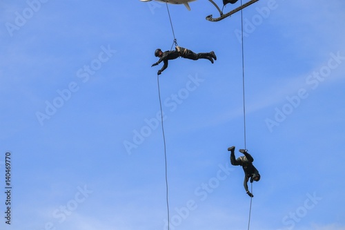 Soldier rappelling from helicopter in blue sky