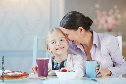 Senior female and her happy granddaughter having dessert and drinks