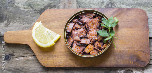 Octopus can with sauce on a table in rustic wooden table