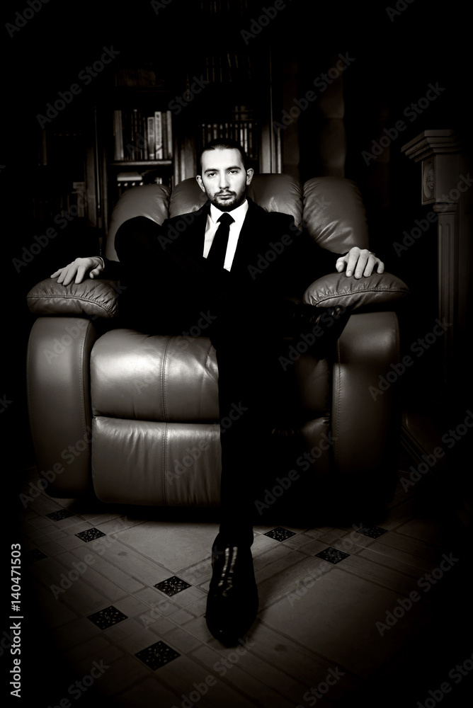 Respectable handsome man sits in a leather chair.