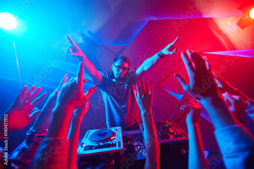 Deejay and crowd raving in disco club