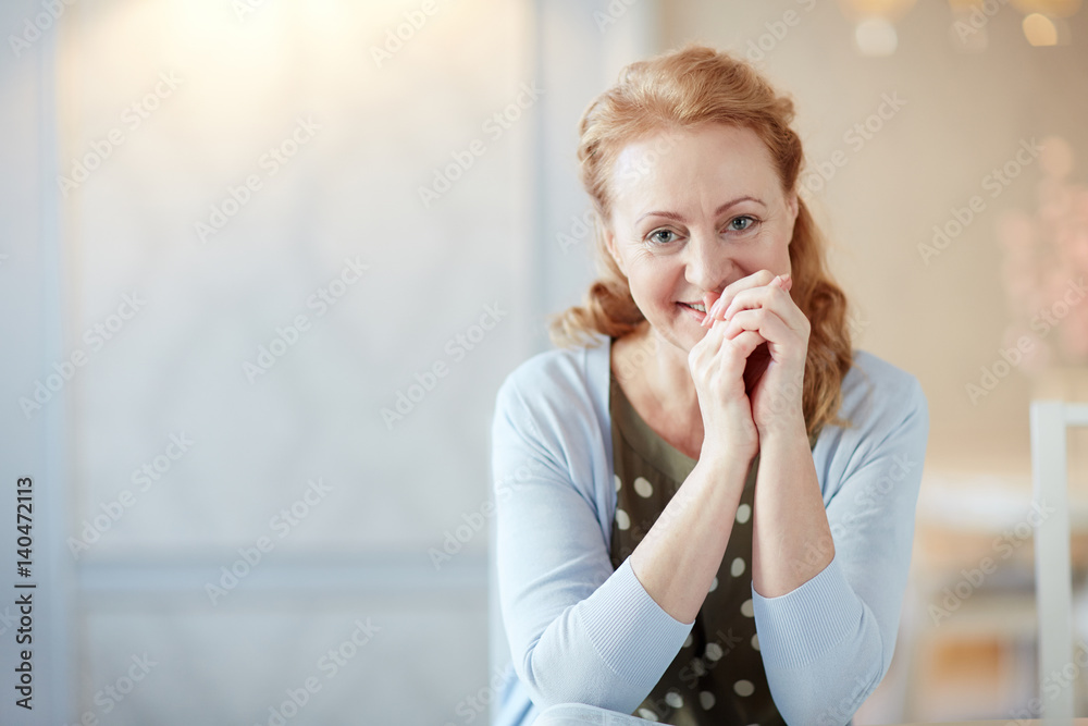 Portrait of beautiful mature woman with long hair smiling gently looking at camera in elegant home interior Portrait of beautiful mature woman with long hair smiling gently looking at camera in elegant home interior