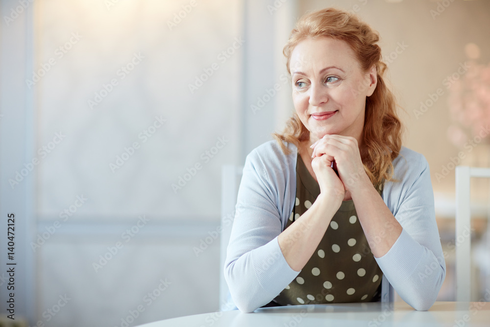 Portrait of elegant mature woman looking away smiling gently in home interior, copy space Portrait of elegant mature woman looking away smiling gently in home interior, copy space