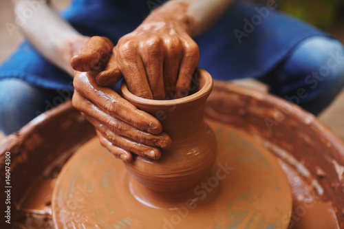 Hands of professional potter making jugs in workshop