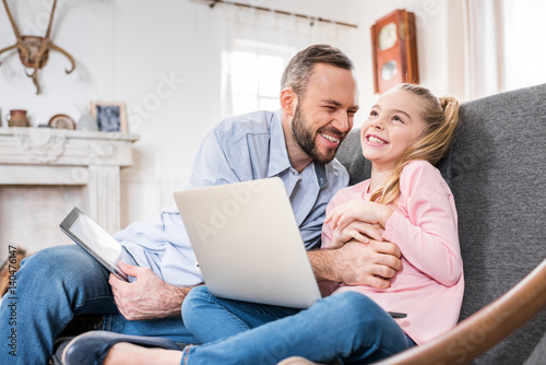 Father and daughter using devices