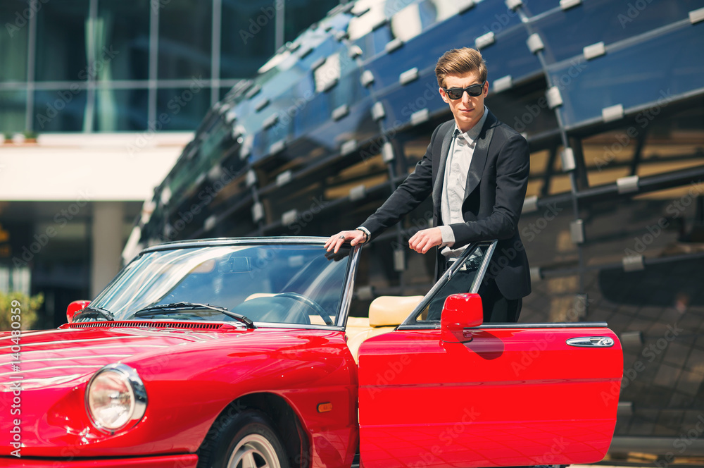 Fashion man standing near retro cabriolet car outdoors