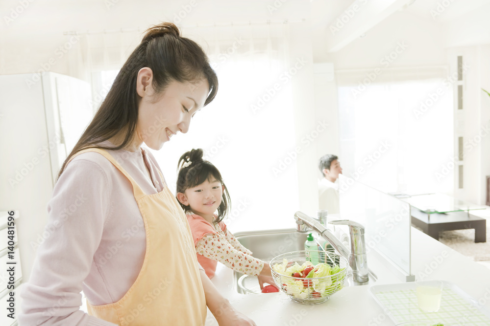 Mother and Daughter Cooking, Father in Background Mother and Daughter Cooking, Father in Background
